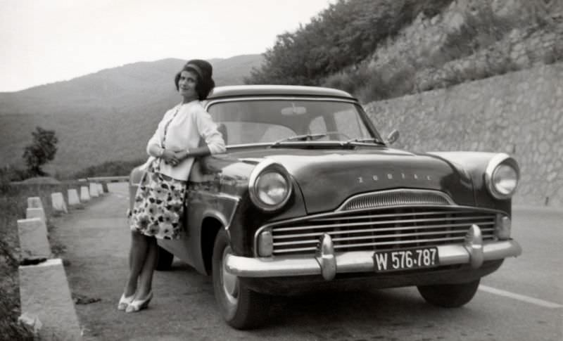 A stylish lady posing with a Ford Zodiac MK II on a mountain road. The car is registered in the city of Vienna, 1965