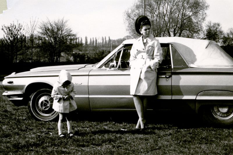 A young mother and her daughter posing with a 1964 Ford Thunderbird Convertible on a sunny day in early spring, 1968
