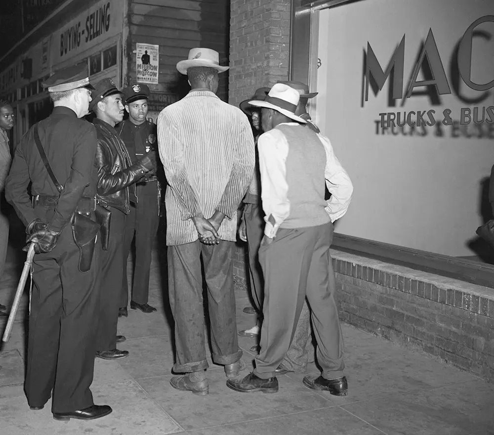 Los Angeles policemen examine draft credentials, as they continue the roundup of zoot suit suspects in the aftermath of the rioting.