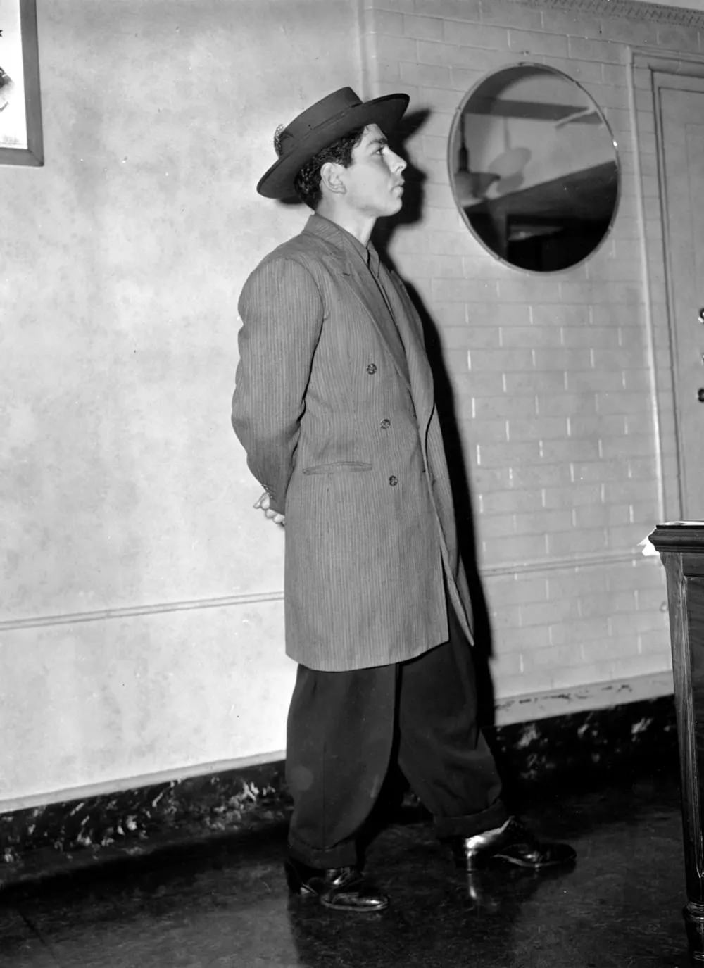 A man arrested during the Zoot Suit Riots models a zoot suit and pancake hat in a Los Angeles County jail on June 9, 1943.