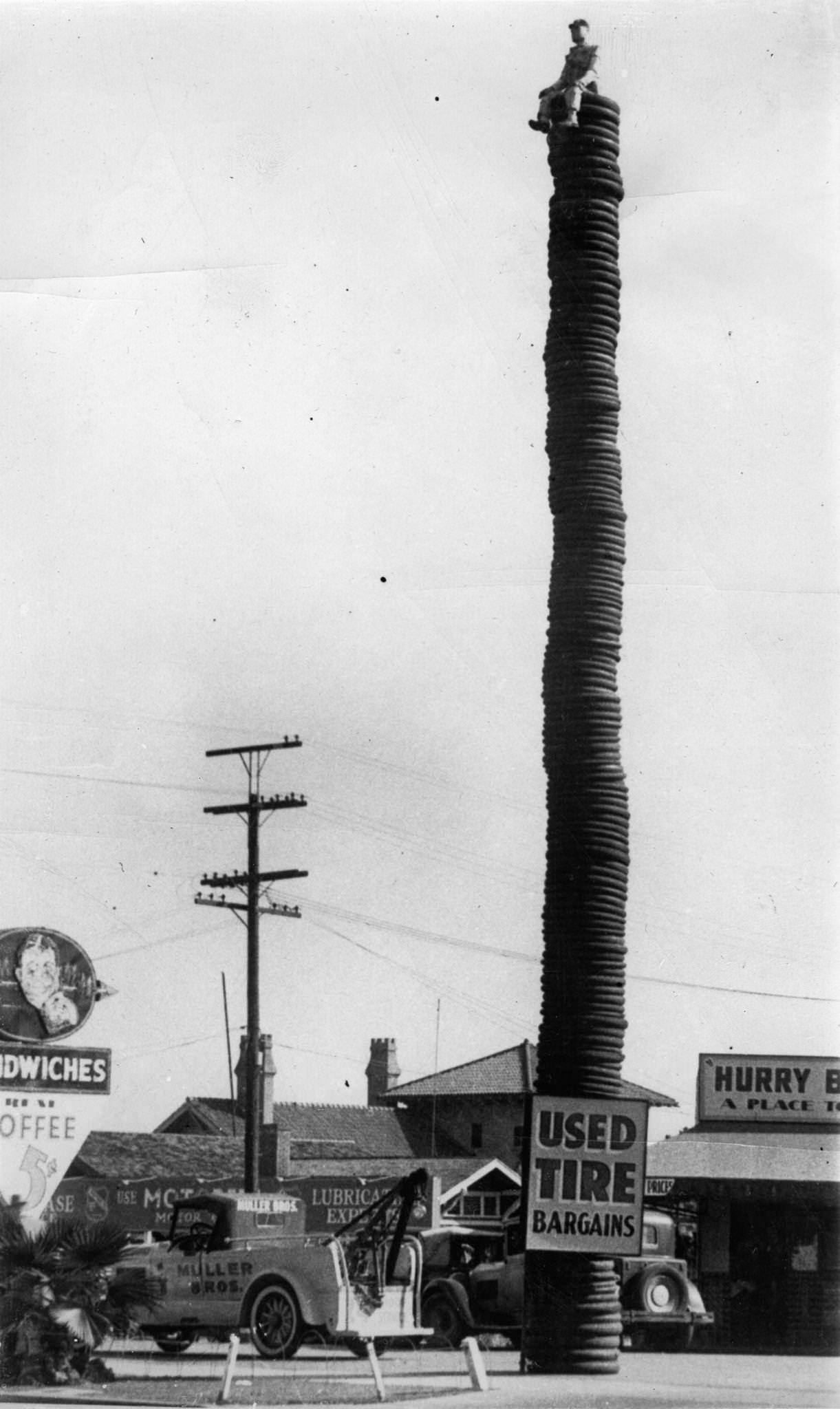 A record breaking stack of tires is used as advertisement at Hollywood, California. To attract attention to a large stock of used tires two salesmen put a lifelike dummy sitting on the top. 2044