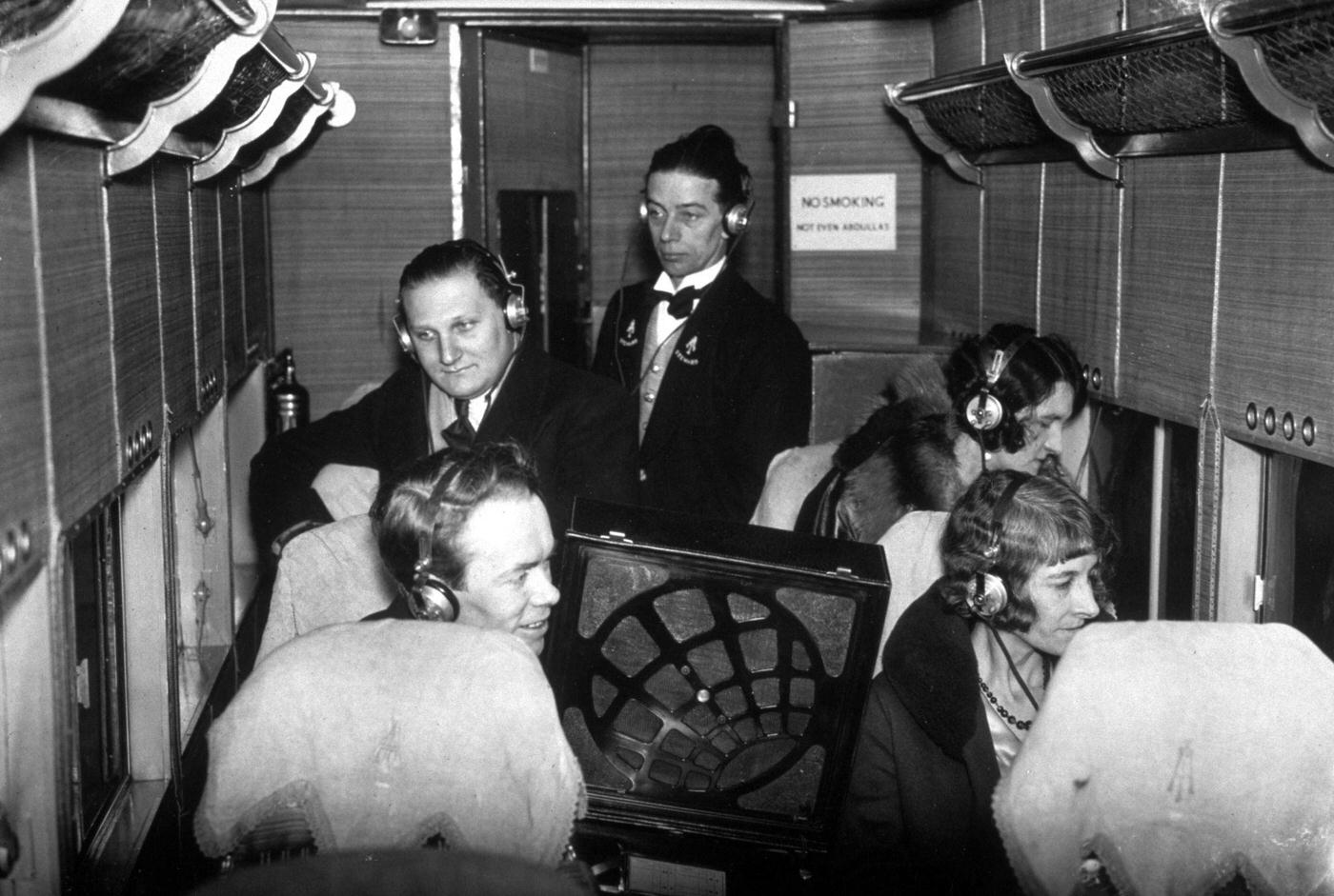 Aeroplane passengers with headphones listening to the first test broadcast of a new service which will enable them to hear and watch the boat race from the air.