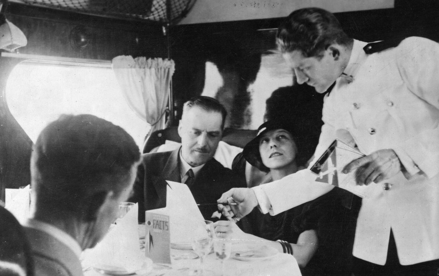 A waiter serves passengers aboard the Imperial Airways 'Scylla' flight from London to Paris.