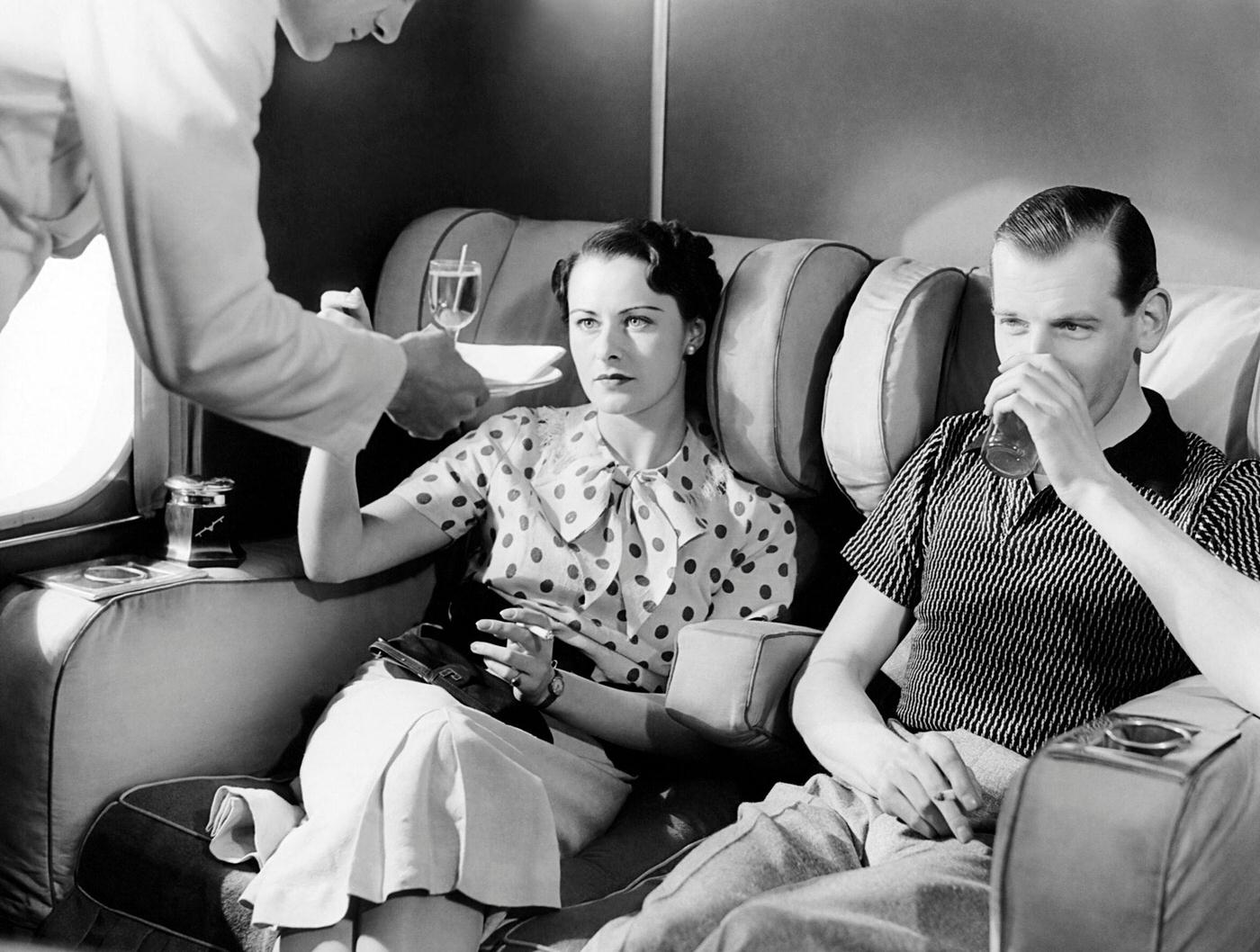 A couple enjoys cocktails in the smoking lounge of the new Imperial Airways Empire flying boat passenger plane in London, 1930