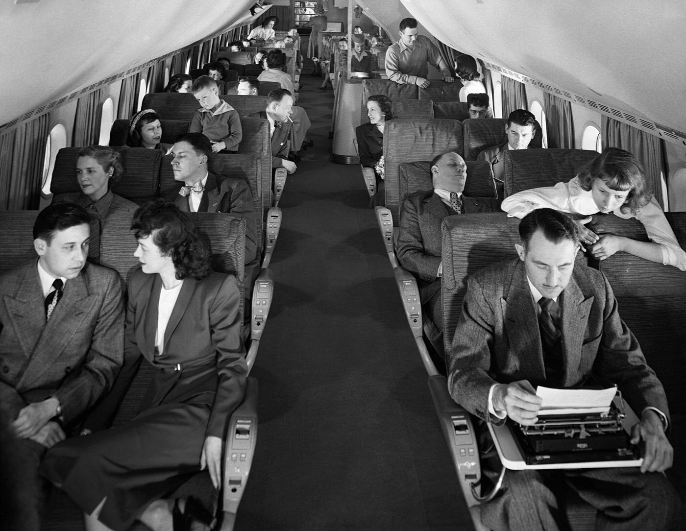 Passengers are seen in the cabin of a Boeing 377 Stratocruiser.