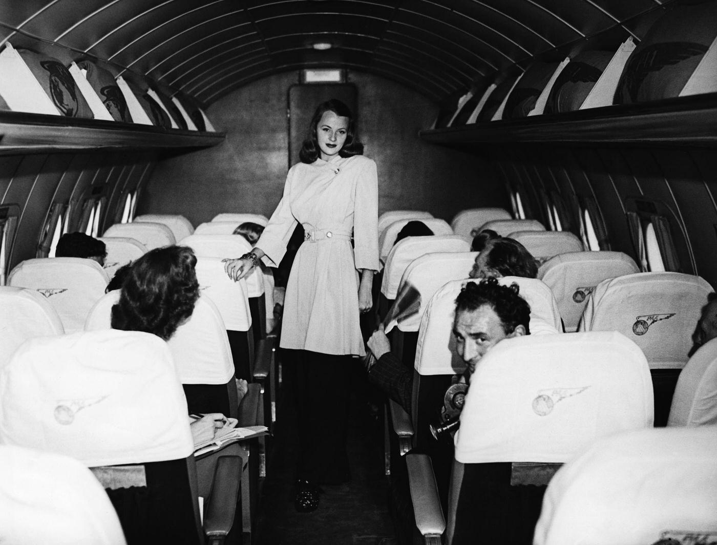 In July 1946, June Fogg models a black-and-white lounge suit during a fashion show staged on board a Pan American Airways Clipper aeroplane during its transatlantic flight from the USA.