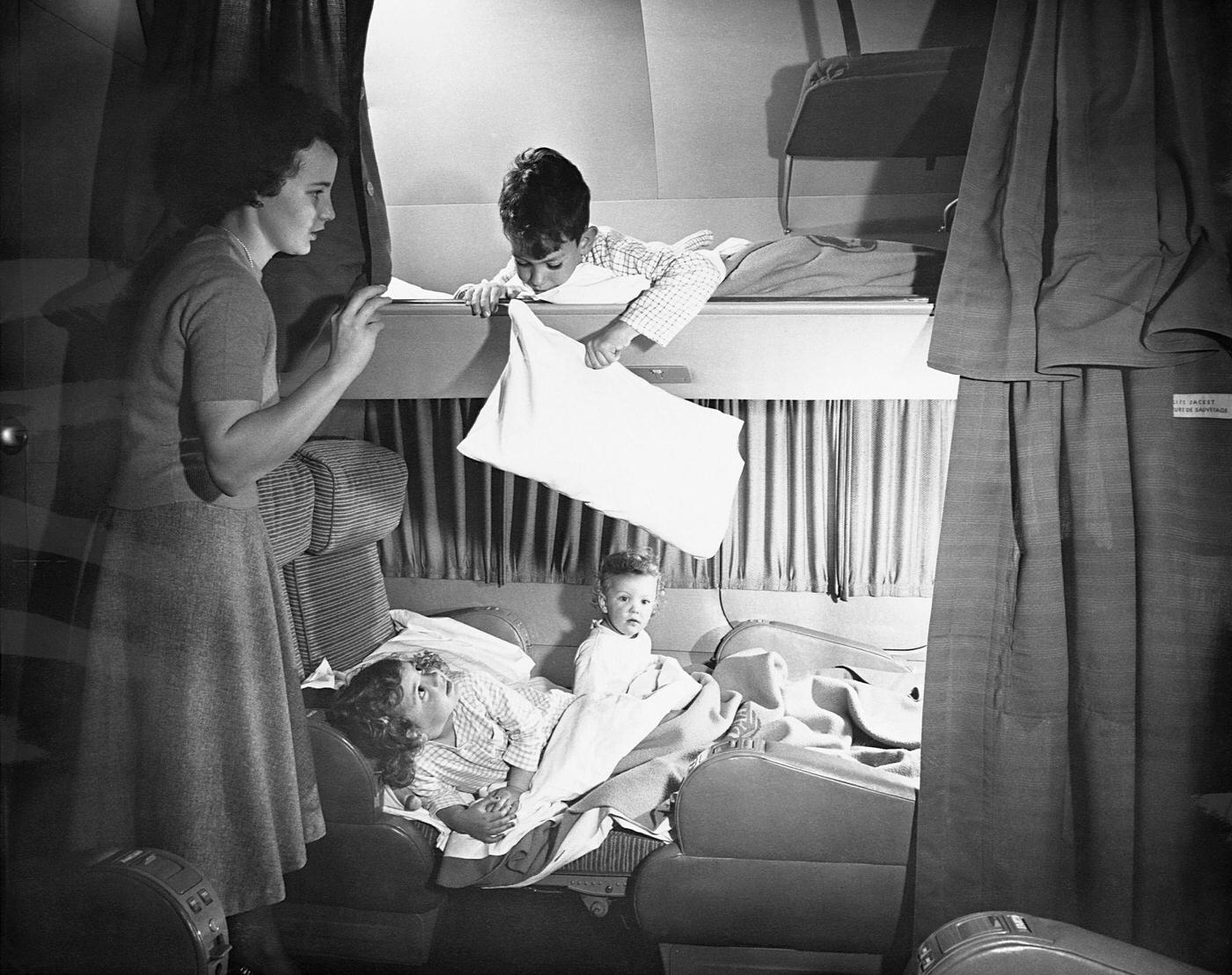 In 1949, a mother is pictured tucking in her children in bunks aboard a Pan American Airways' Boeing 377 Stratocruiser.