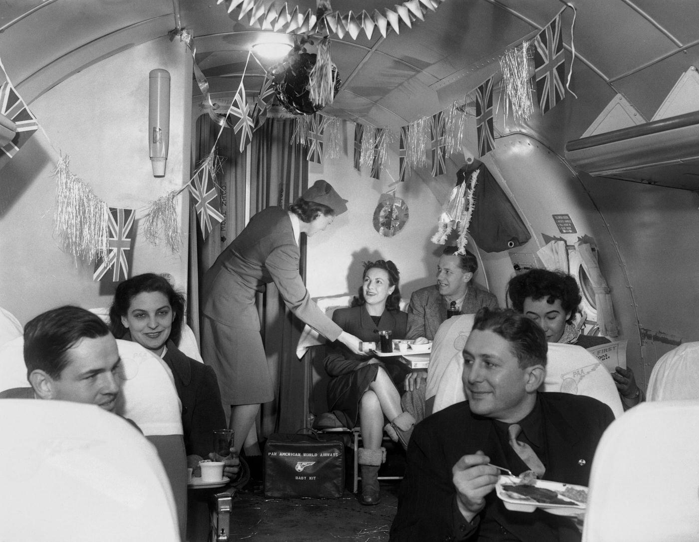 Air hostess Patricia Pelley is serving an in-flight meal to passengers traveling across the Atlantic on board a festively decorated, Pan-American aeroplane.