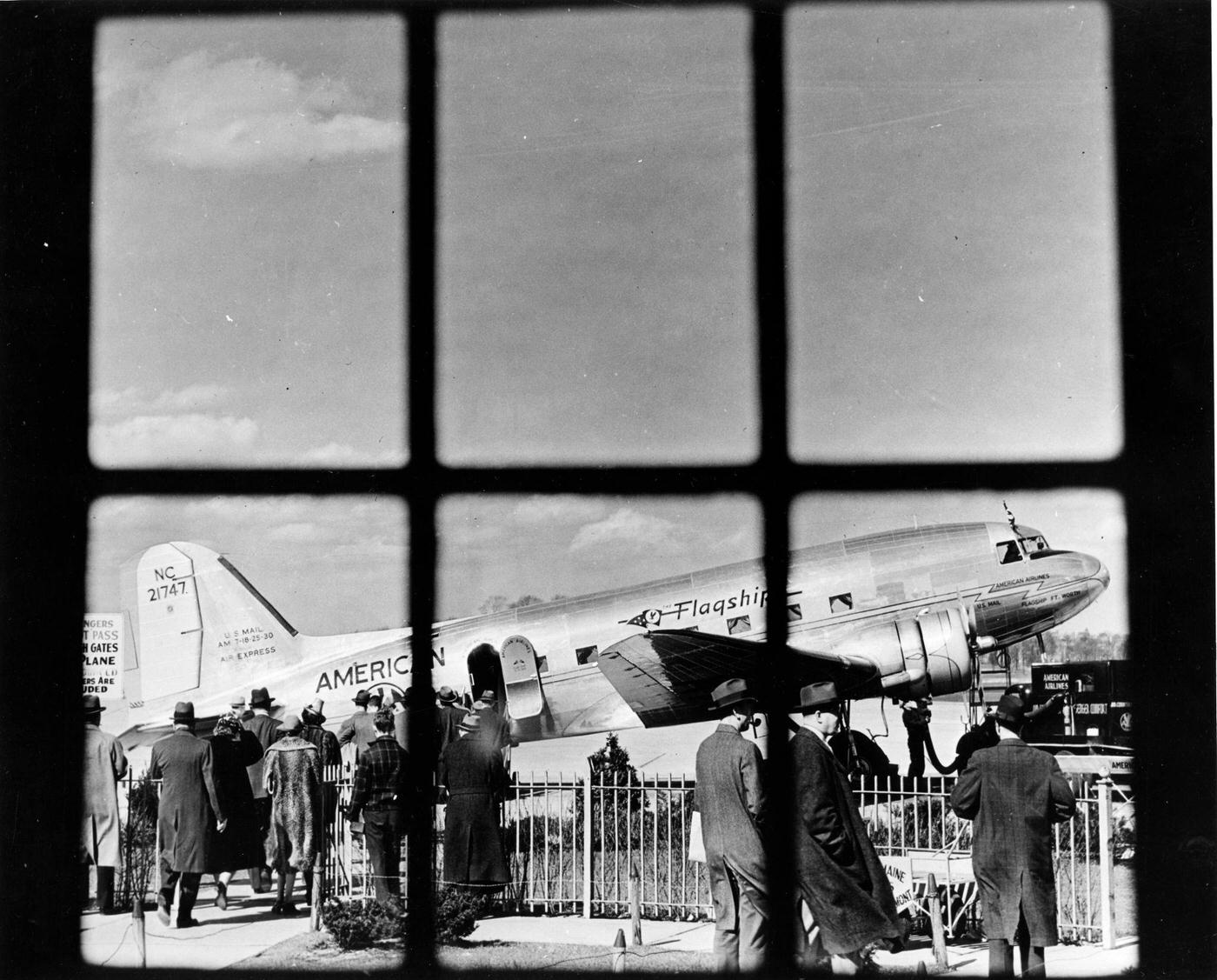 Through a window of the terminal at LaGuardia Airport, passengers are boarding an American Airlines' 'Flagship' plane on the tarmac in 1946.