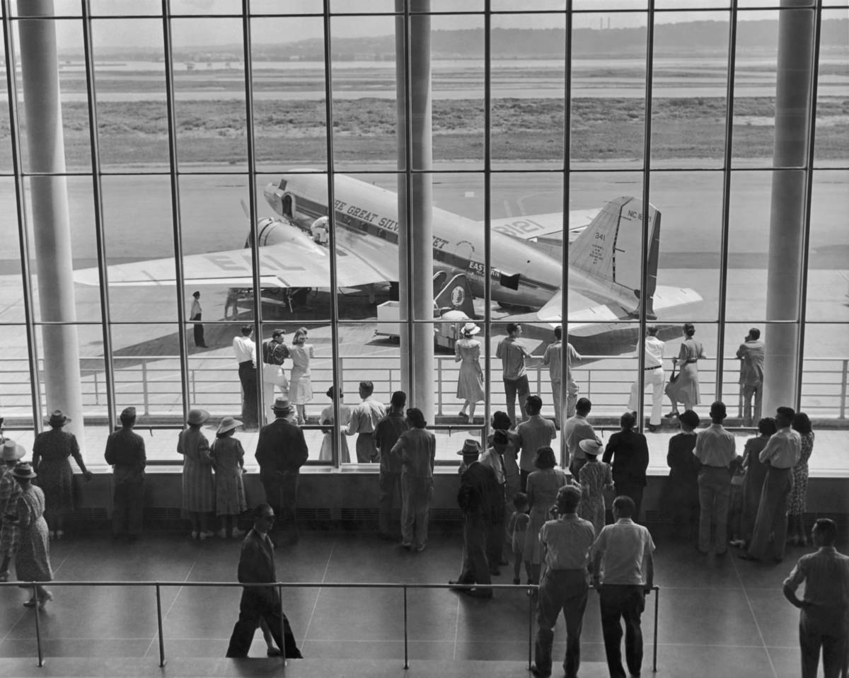 In 1945, a viewing gallery at an airport shows a Douglas DC-3 airliner of Eastern Airlines ('The Great Silver Fleet').