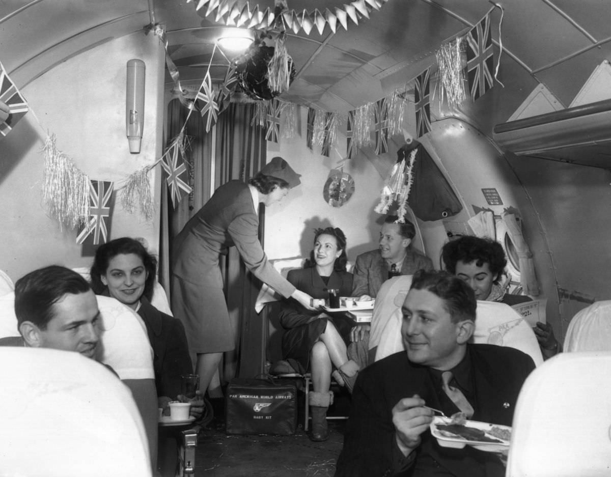 On December 23, 1946, air hostess Patricia Palley attends to passengers in the decorated cabin of a Pan-American airliner over the Atlantic.