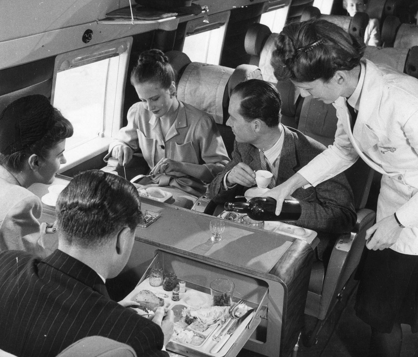 A stewardess serves drinks while passengers have lunch aboard a BEA Vickers Viking passenger plane in 1958.
