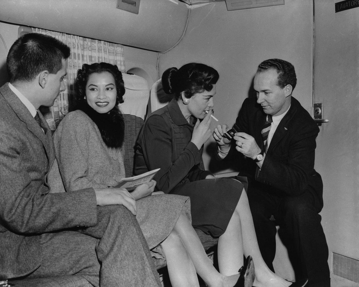 Passengers take a moment to relax and enjoy a cigarette on a Transocean Air Lines Boeing 377 Stratocruiser flight in the mid 1950s. Transocean Air Lines was a pioneering discount airline that operated between 1946 and 1962.