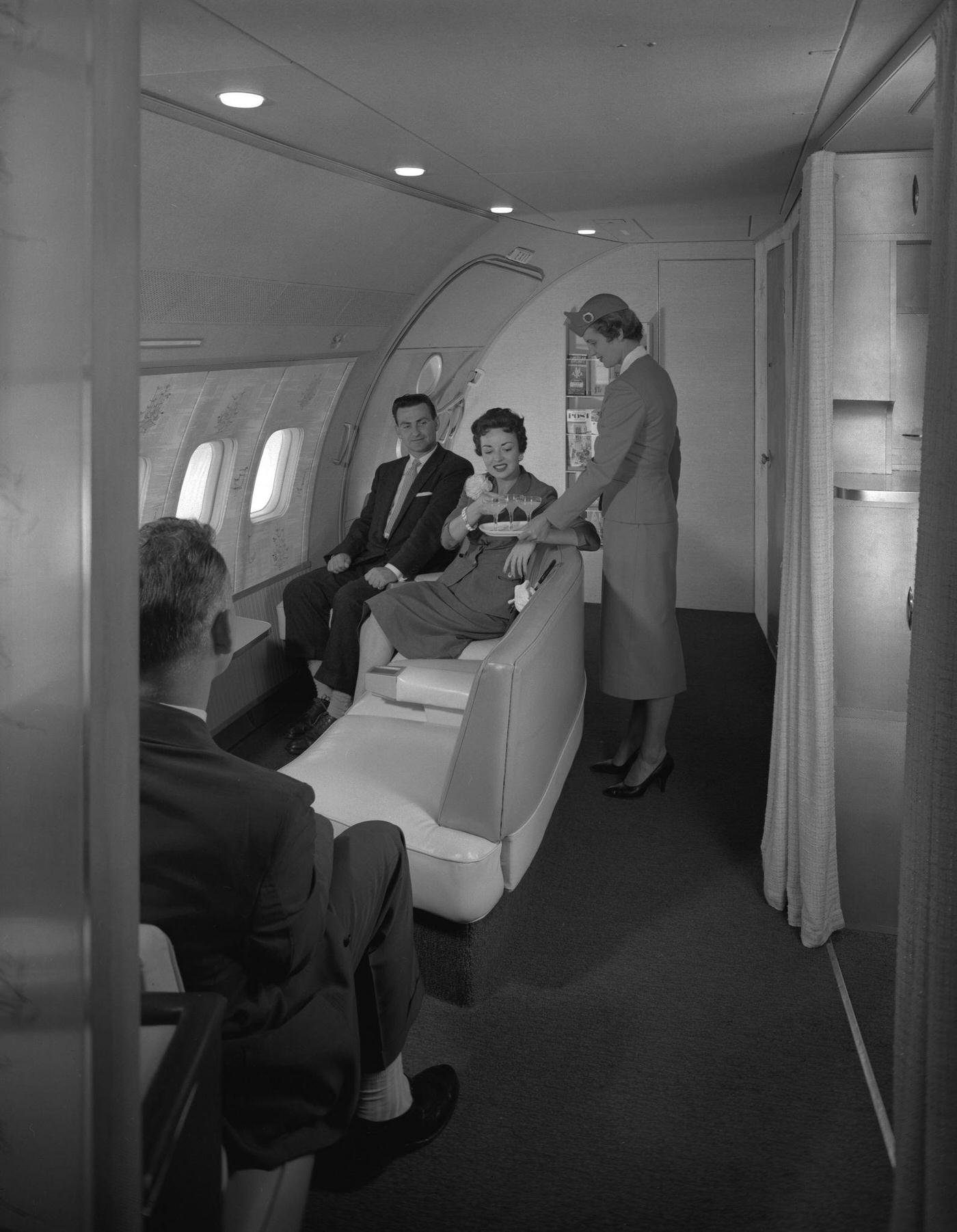 An attentive air hostess serves passengers in the observation area of a Transocean Air Lines Boeing 377 Stratocruiser during a flight in the mid 1950s.