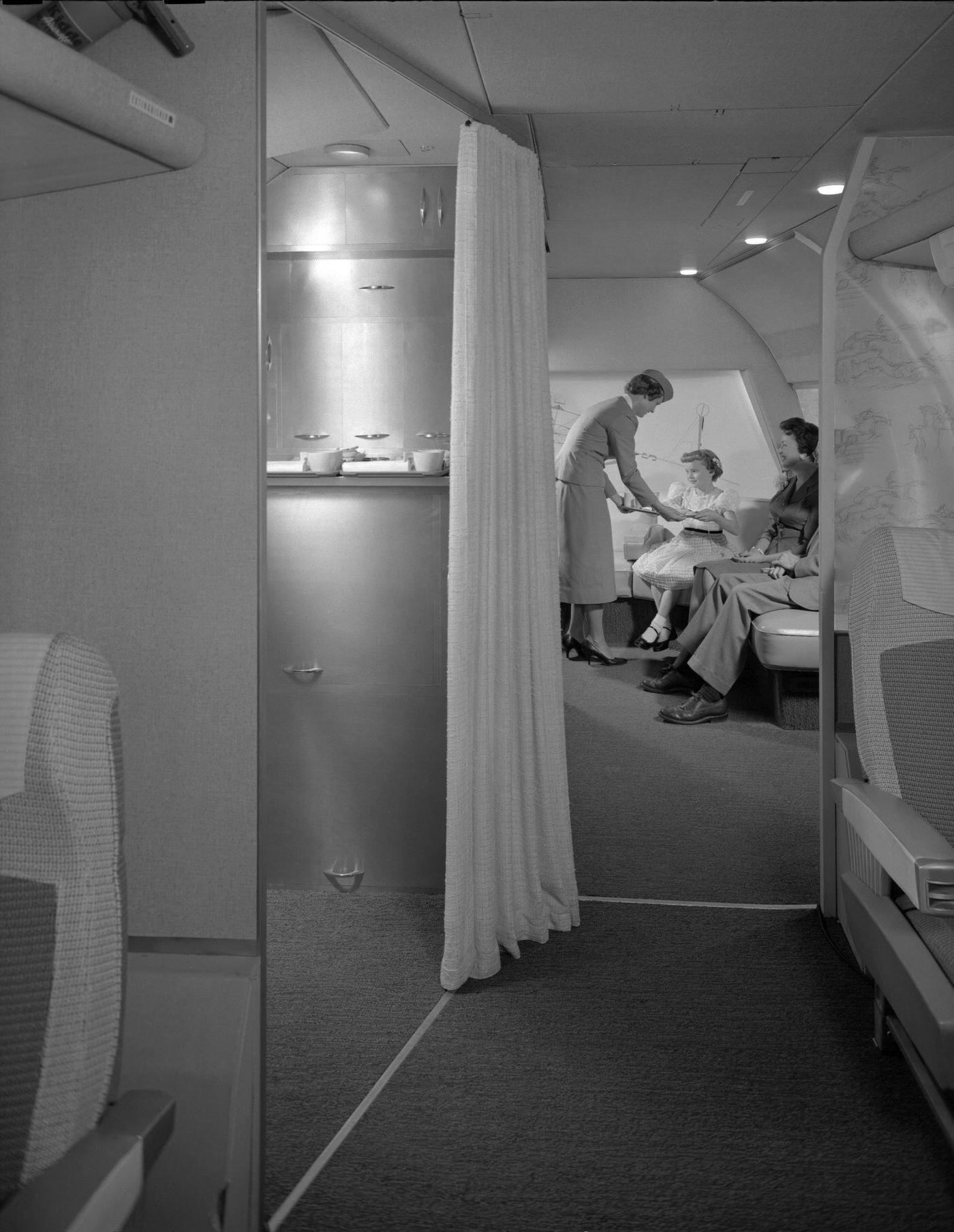 Passengers are treated to excellent service on a Transocean Air Lines Boeing 377 Stratocruiser flight in the mid 1950s as an air hostess serves refreshments in the observation area. Transocean Air Lines was a pioneering discount airline that operated between 1946 and 1962.