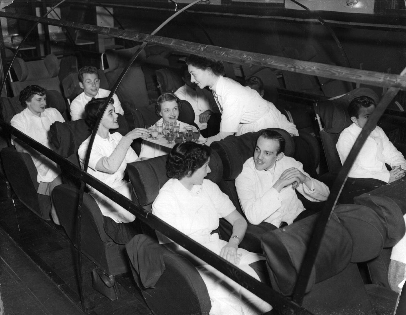 Trainee BOAC cabin crew members simulate being passengers in a replica of a Hermes aircraft during their training near Heston Airport, Middlesex, in 1958.