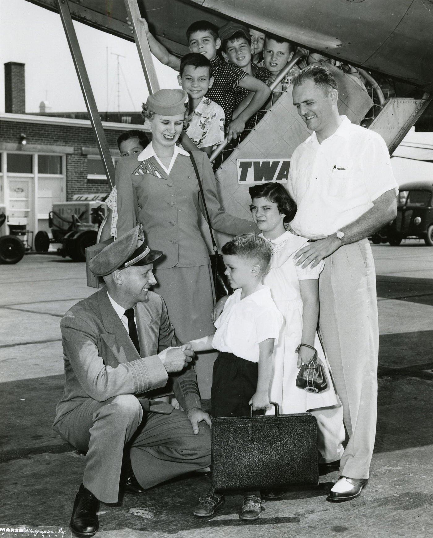 A TWA pilot and stewardess greet passengers disembarking from a plane in the 1950s.