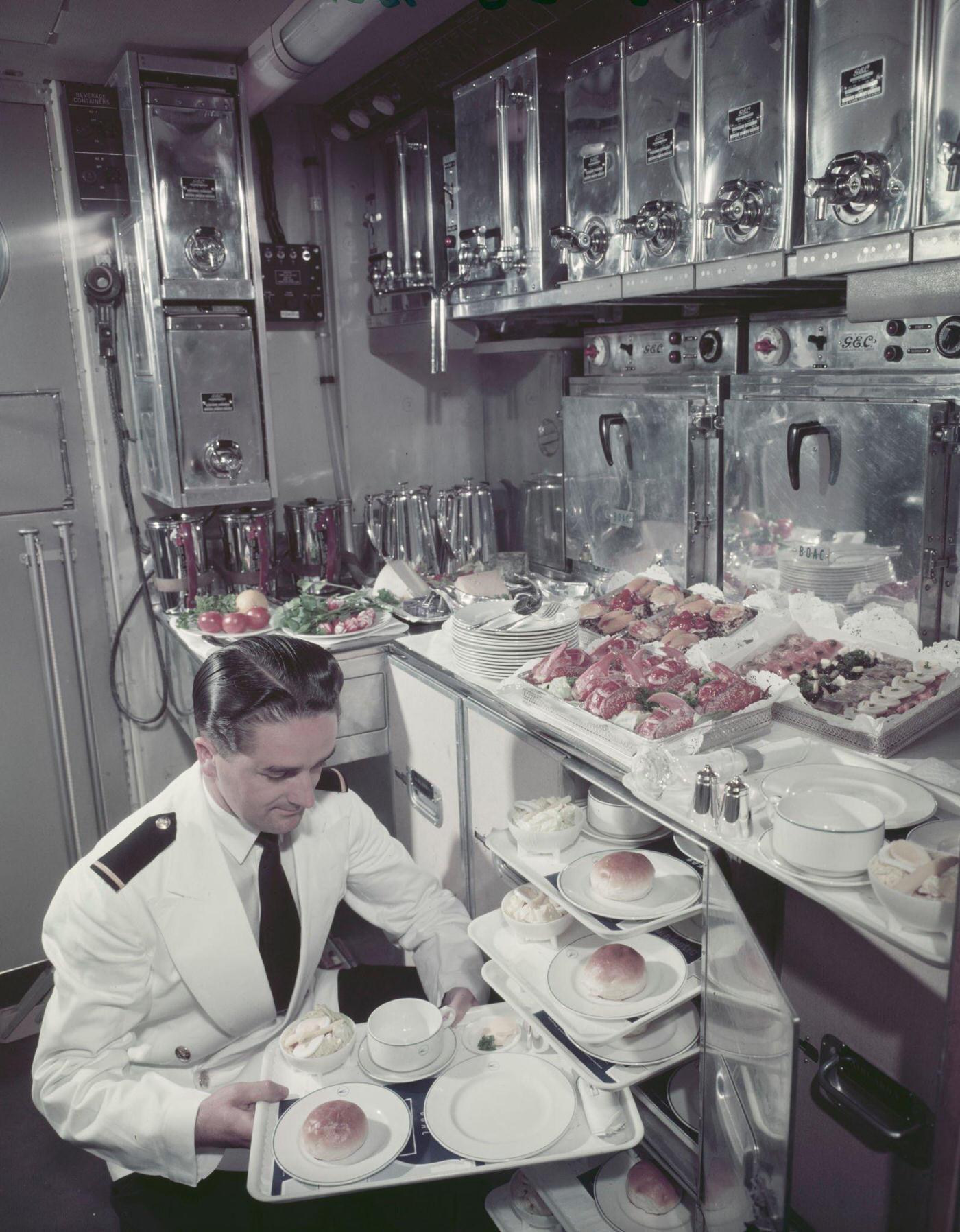 In October 1956, a male air steward prepares a tray of food in the galley for passengers on board a Bristol Britannia medium to long range airliner.