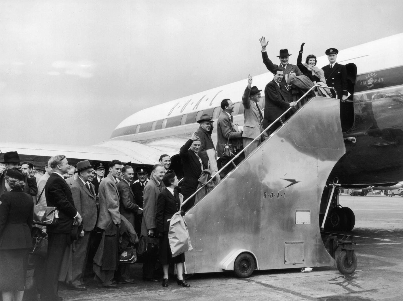 Passengers bound for Johannesburg board the inaugural British Overseas Airways Corporation (BOAC) De Havilland Comet jet airliner at London Airport, marking the world's first regular jet service.