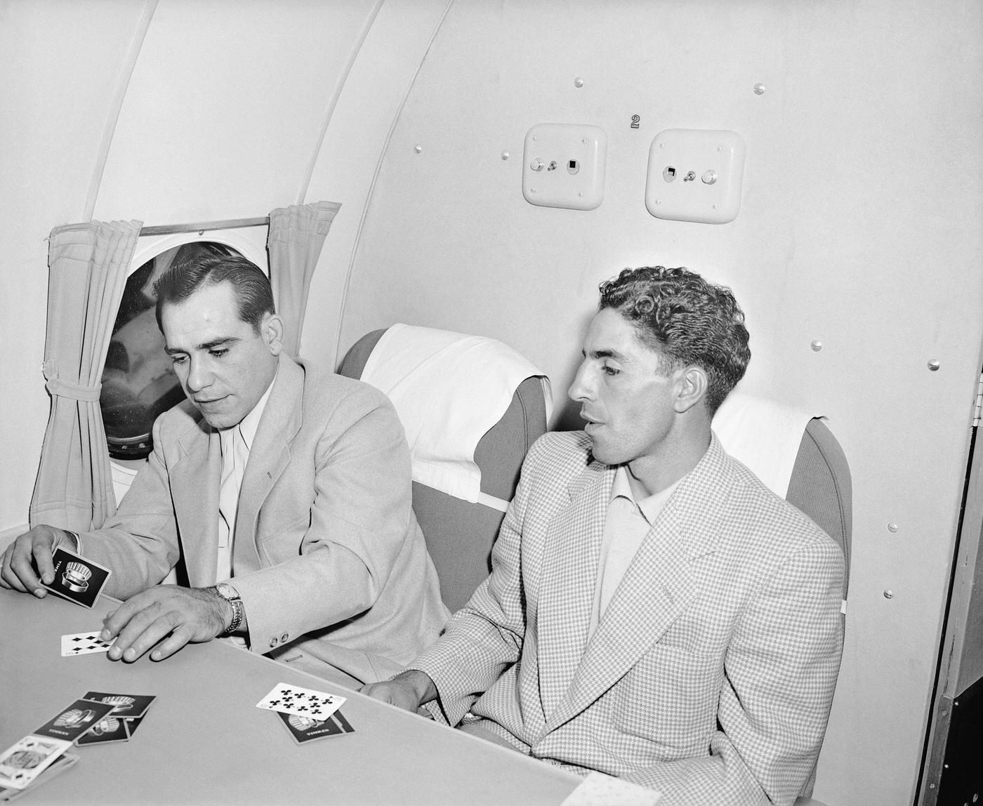 Yankee catcher Yogi Berra and Phil Rizzuto play cribbage while waiting for chartered TWA flights to take off amidst a railroad strike.