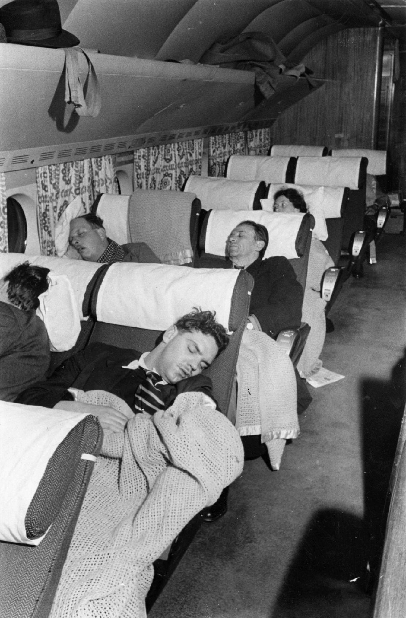 Travellers sleep on board an airplane in New York, as seen in this 1950 photo from Picture Post.
