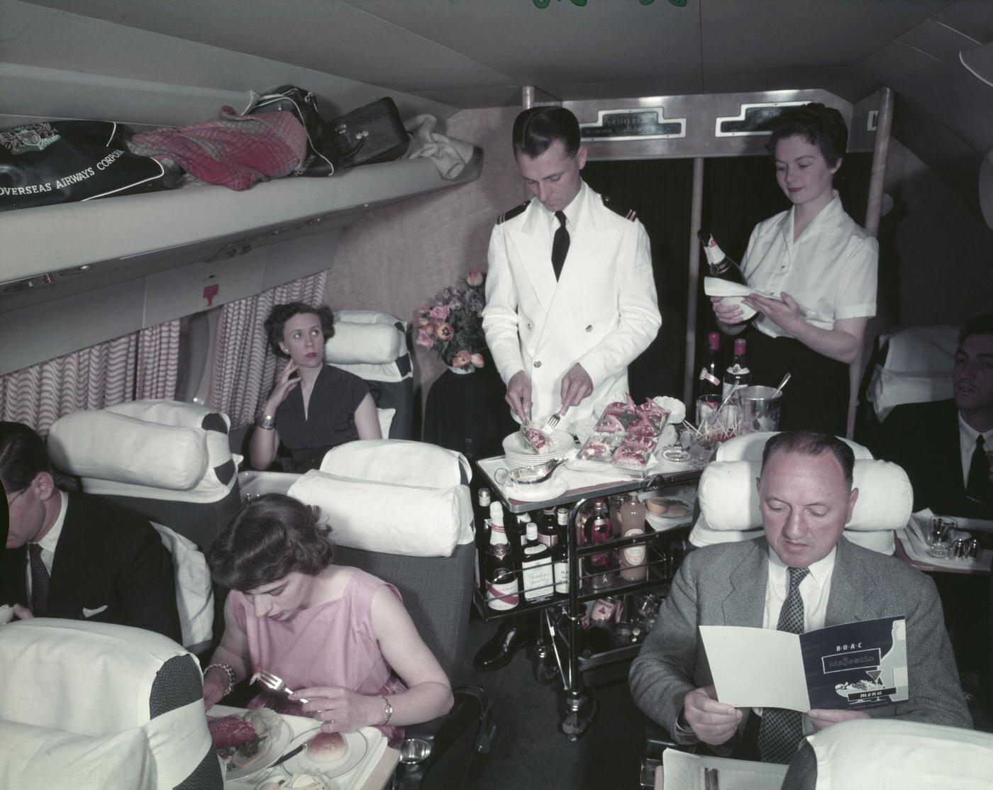 In October 1956, a male air steward and female air stewardess serve food and drinks from a trolley to passengers on board a Bristol Britannia medium to long range airliner.