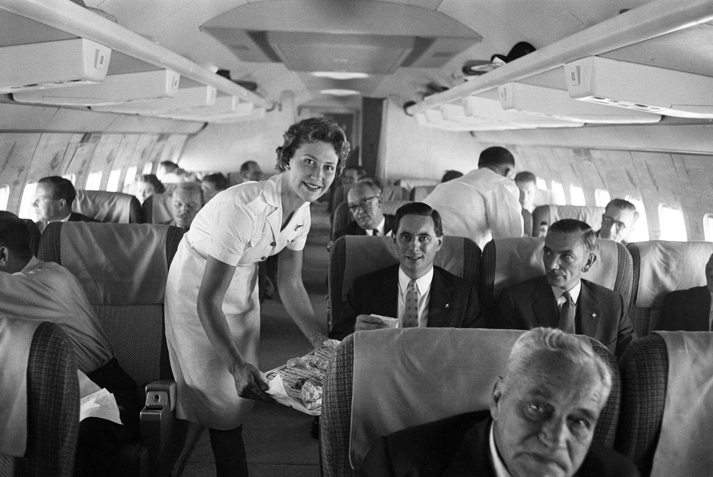 On August 7, 1959, an air stewardess serves food to passengers on board a Qantas Boeing 707 plane at London airport.