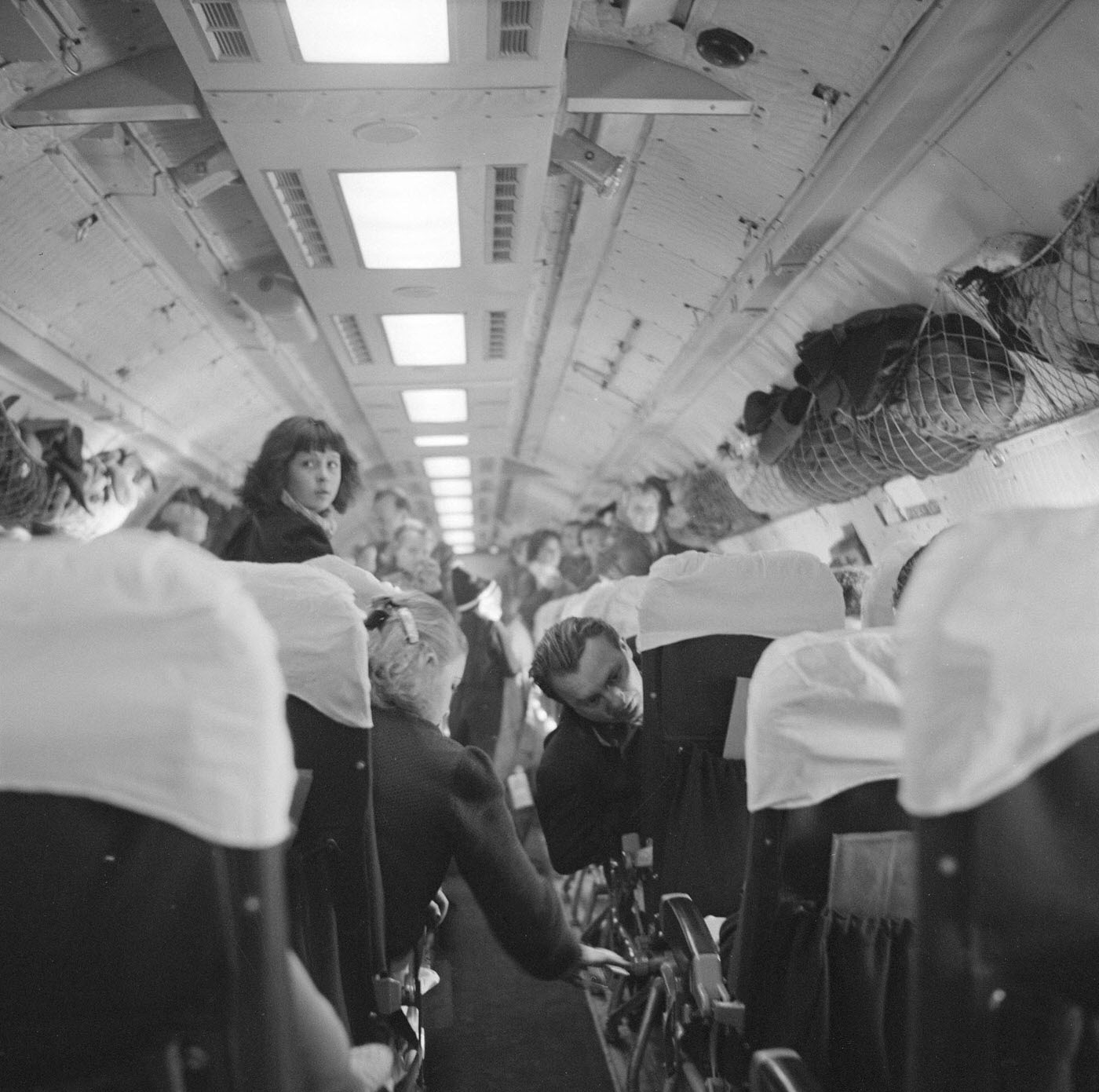 In 1957, a view of airline passengers is seen along the center aisle of a plane. Many of the passengers are refugees from the failed Hungarian Revolution and are on their way to the United States.