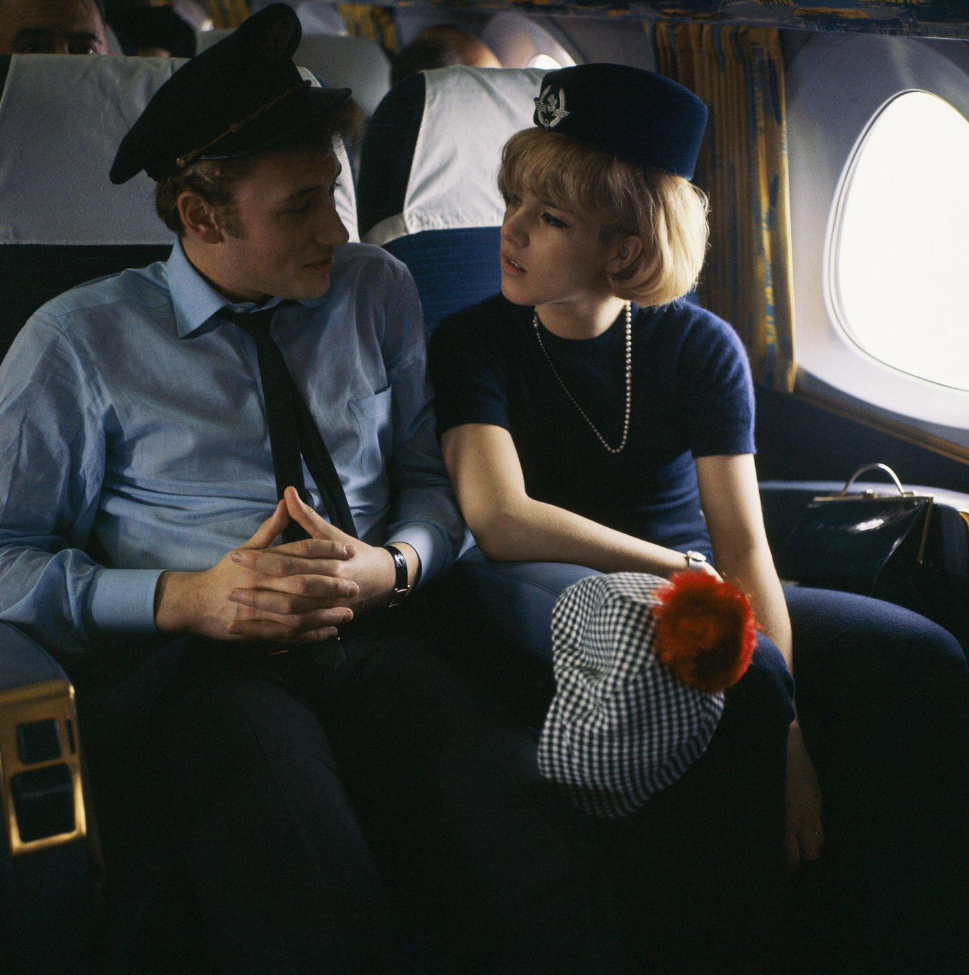 Sylvie Vartan and Johnny Hallyday in an airplane in 1963, with Vartan wearing a flight attendant's hat and Hallyday wearing a pilot's cap.