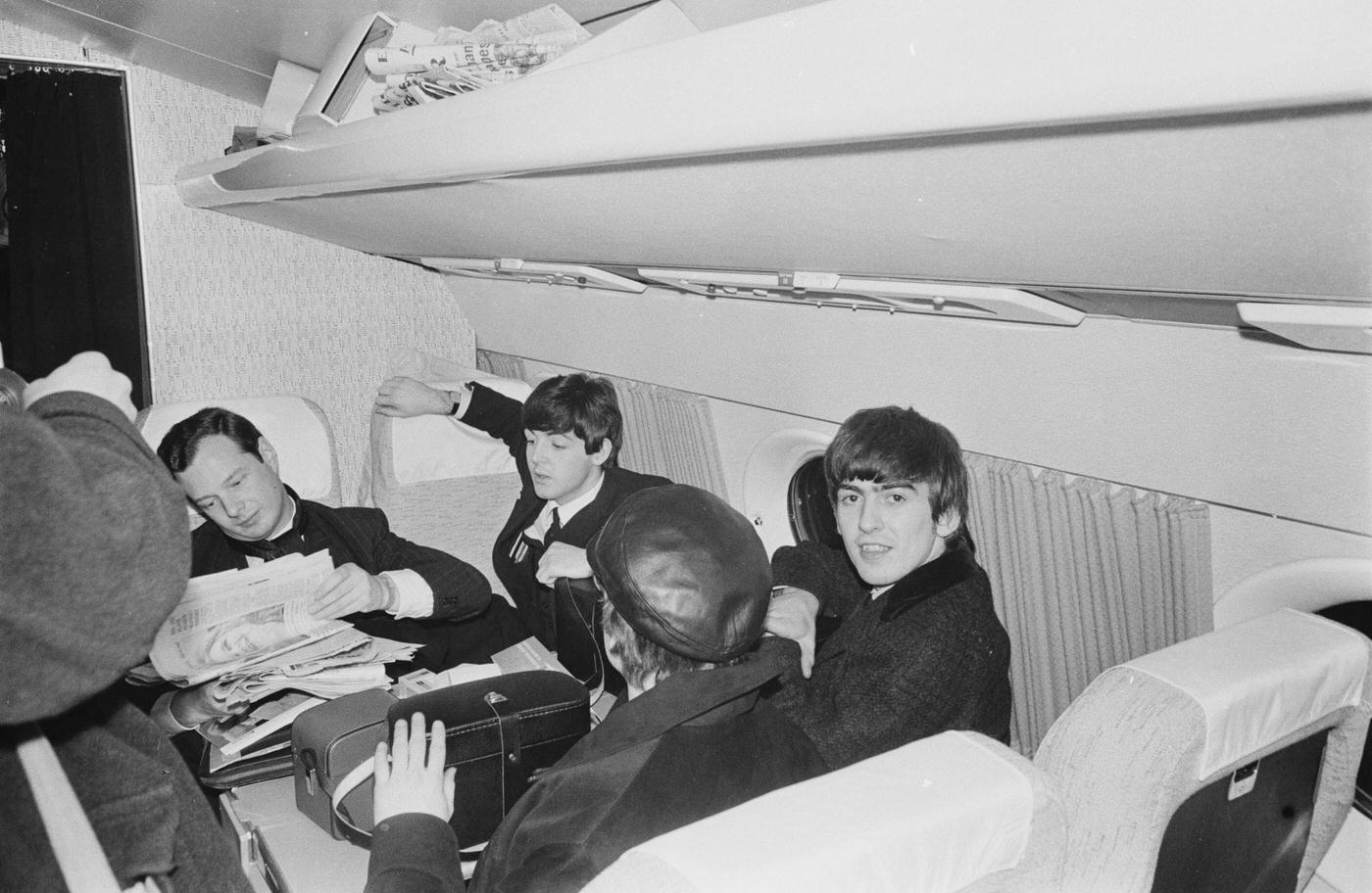 Members of The Beatles on board a plane bound for Paris in January 1964, left to right: manager Brian Epstein, Paul McCartney, John Lennon, and George Harrison.