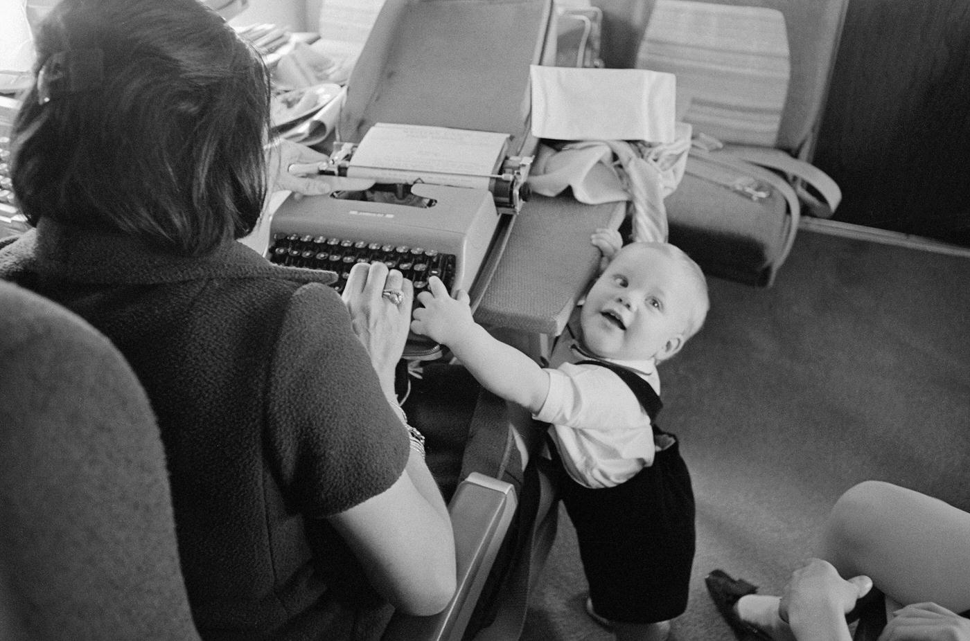 President Lyndon Johnson's grandson, Patrick Lyndon, typing on a typewriter with journalist Helen Thomas on Air Force One during a flight to New York City in the 1960s.