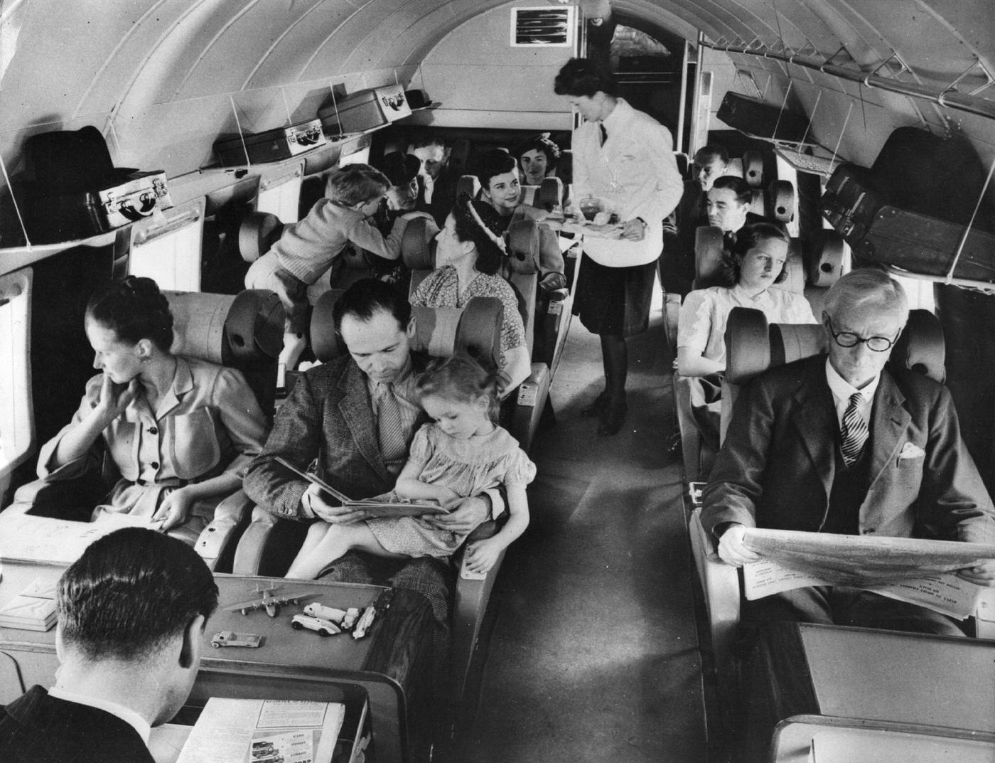 Interior of a BEA Vickers airplane showing the passenger section; a stewardess is about to serve lunch. 1960.