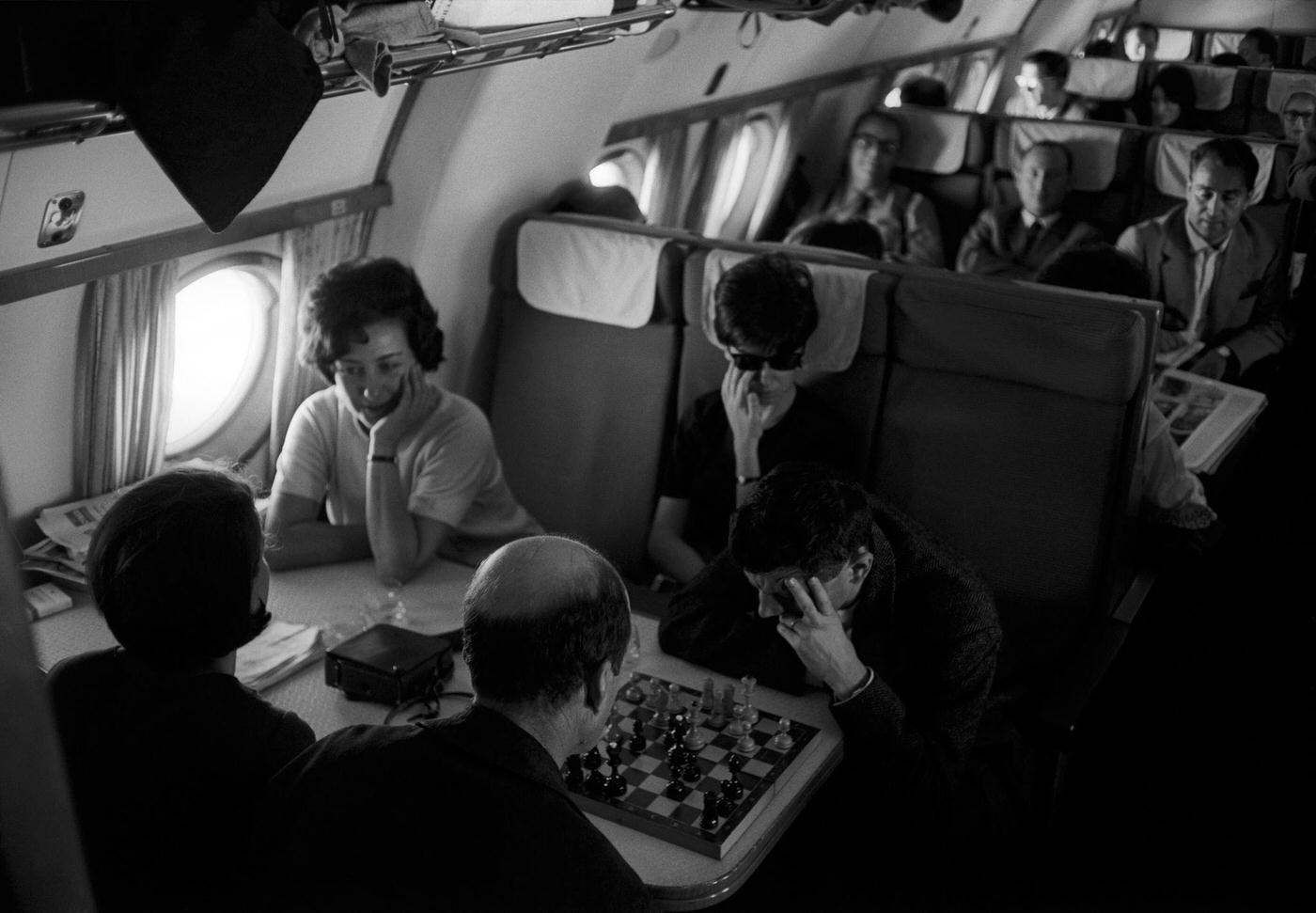 Actors from the Teatro alla Scala company relaxing by chatting and playing chess during air travel in September 1964.