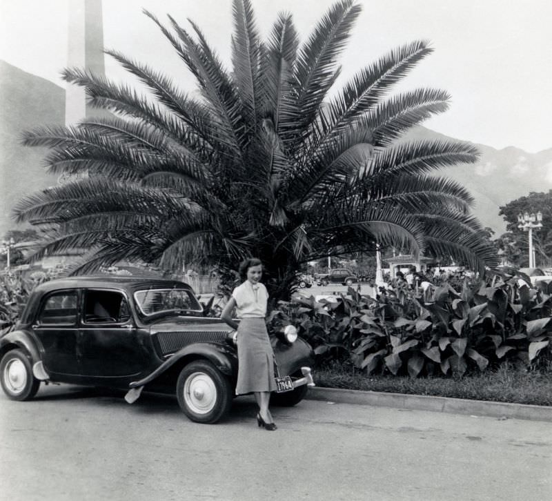 Lady with Citroën 11 CV under palm tree in exotic location, July 1951