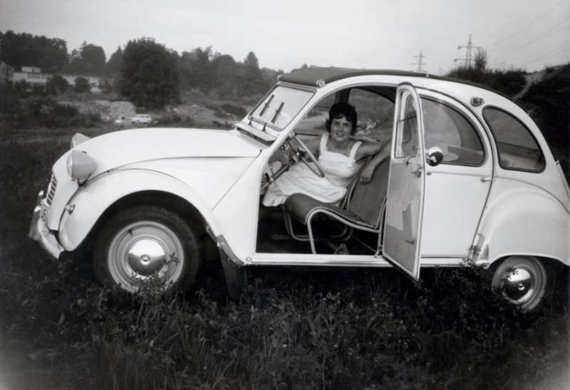 Brunette lady with Citroën 2CV in hammock-style seats, 1965