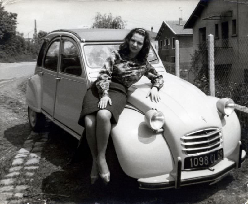 Brunette lady on fender of Citroën 2CV in suburban street, Rhône registration, 1965