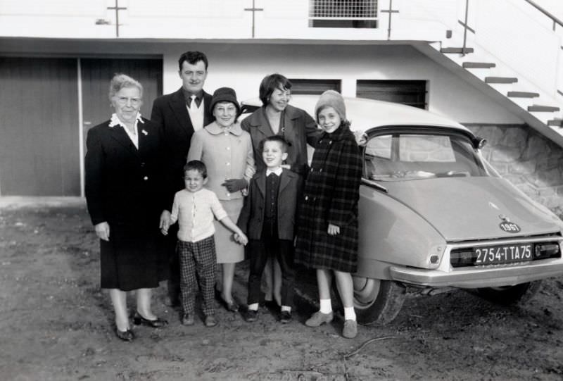 Seven members of a French middle-class family posing with a Citroën DS in the drive of a private home, 1965