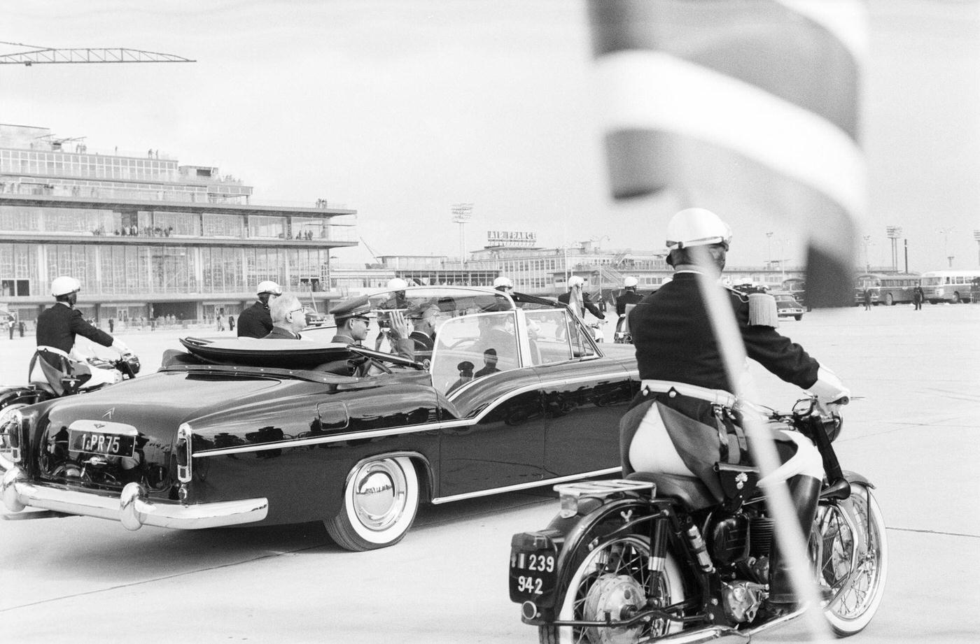 King Bhumibol and Queen Sirikit of Thailand in a presidential Citroën Traction Avant 15-Six H Cabriolet escorted by motorcyclists in France, 1960.