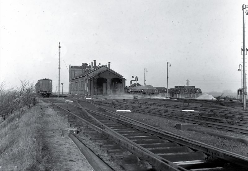 A view over the yard that protrudes above the bare polder plain to the workshop and locomotive shed of Uithoorn with the coal park, wagons with and for coal and the water column, February 22, 1950