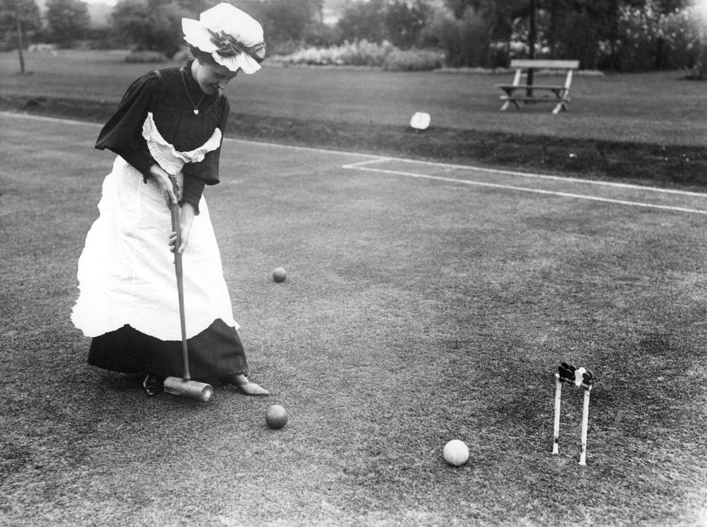 A group of Edwardian ladies and gentlemen playing croquet on a sunny day