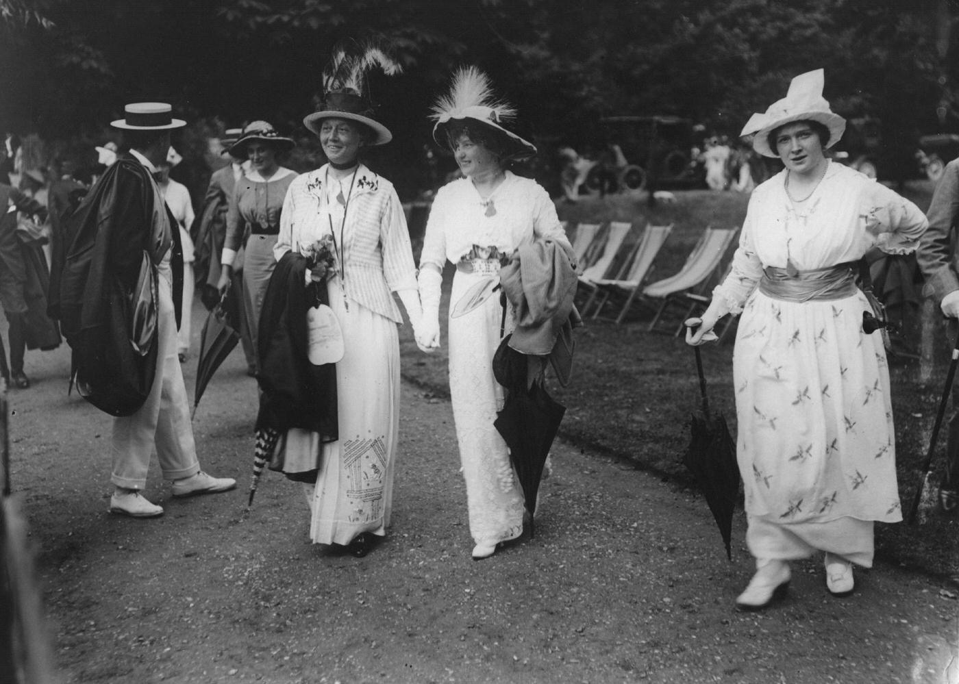 A group of women donning fashionable dresses and hats of the Edwardian era