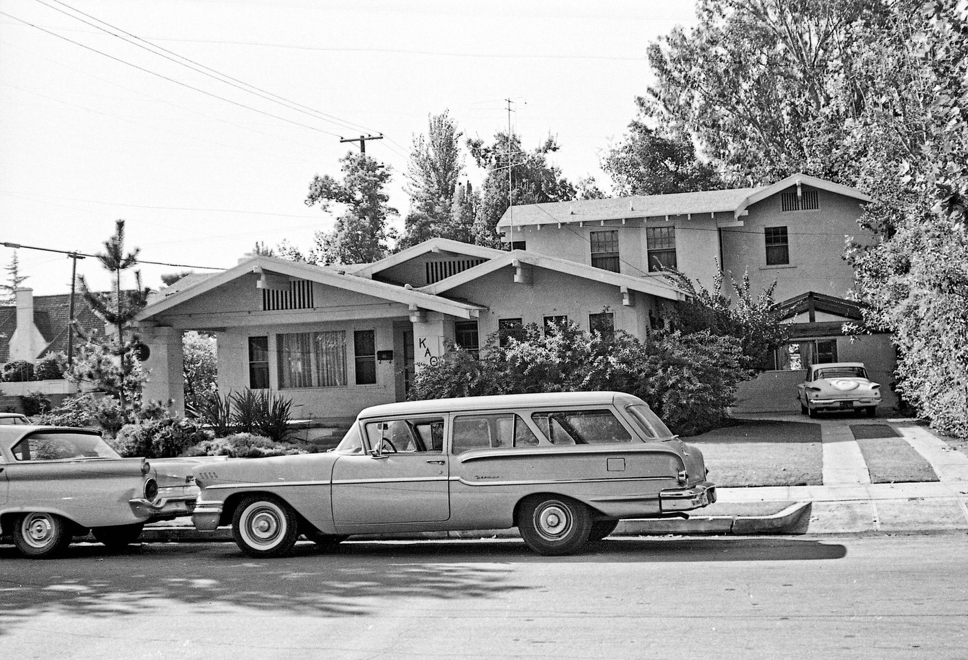 A 1958 Chevy parked on street behind a 1959 Ford in front of the Kappa Alpha Theta sorority house in the older part of Fresno near Fresno City College.
