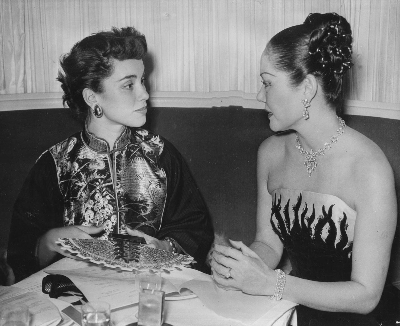 Actress Linda Christian (left) wearing a traditional Chinese jacket and talking to Chinese-born compere Seignon at a Christmas Party held by Chen Yu nail lacquers at the Embassy Club in London, October 28th 1950.