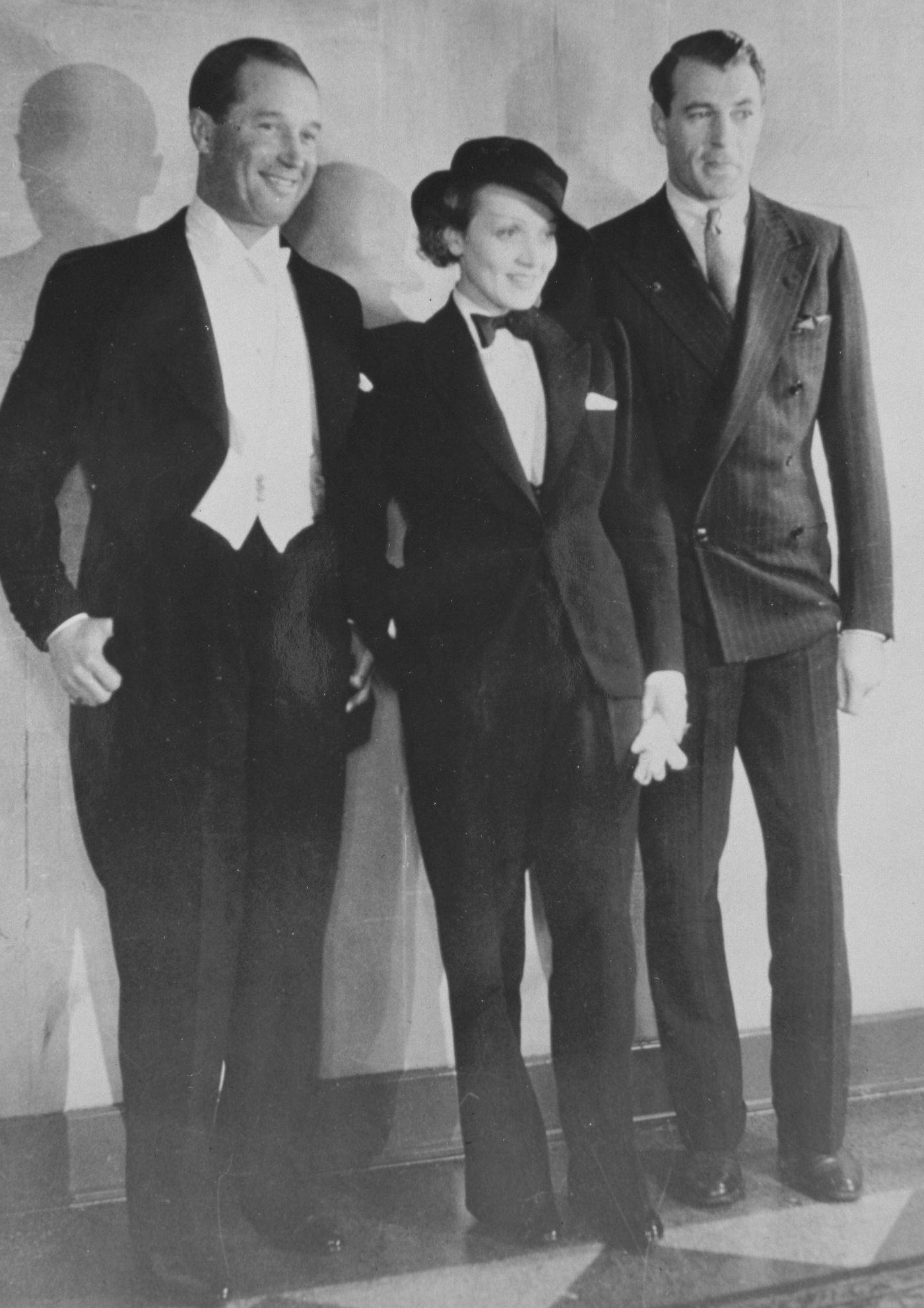Maurice Chevalier (left) and Gary Cooper flank Marlene Dietrich dressed in a tuxedo.