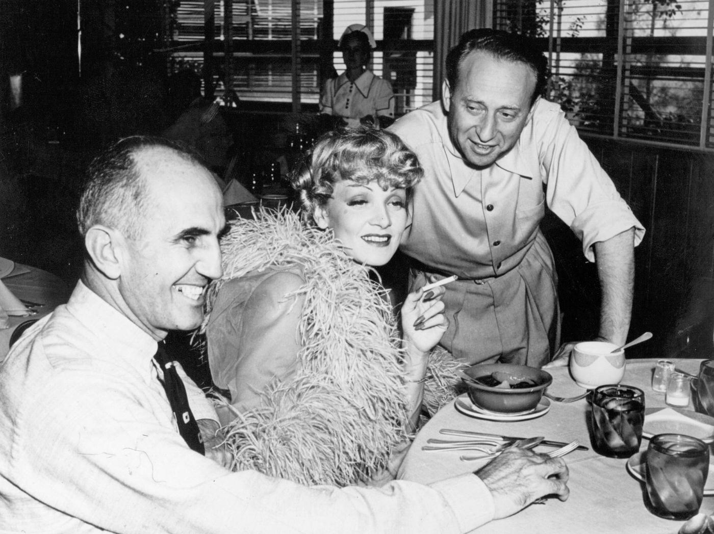 Marlene Dietrich has lunch with director George Marshall and producer Joe Pasternak on the set of her latest film 'Destry Rides Again' in 1939.