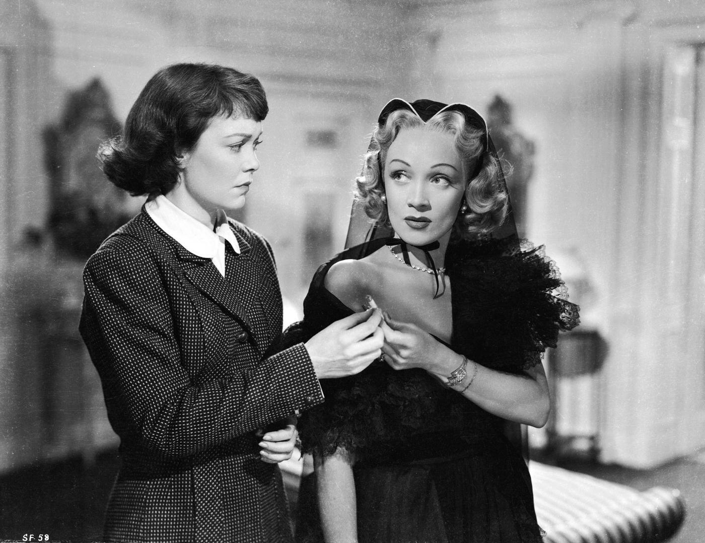Jane Wyman and Marlene Dietrich share a cigarette in a scene from the 1950 murder mystery 'Stage Fright.'