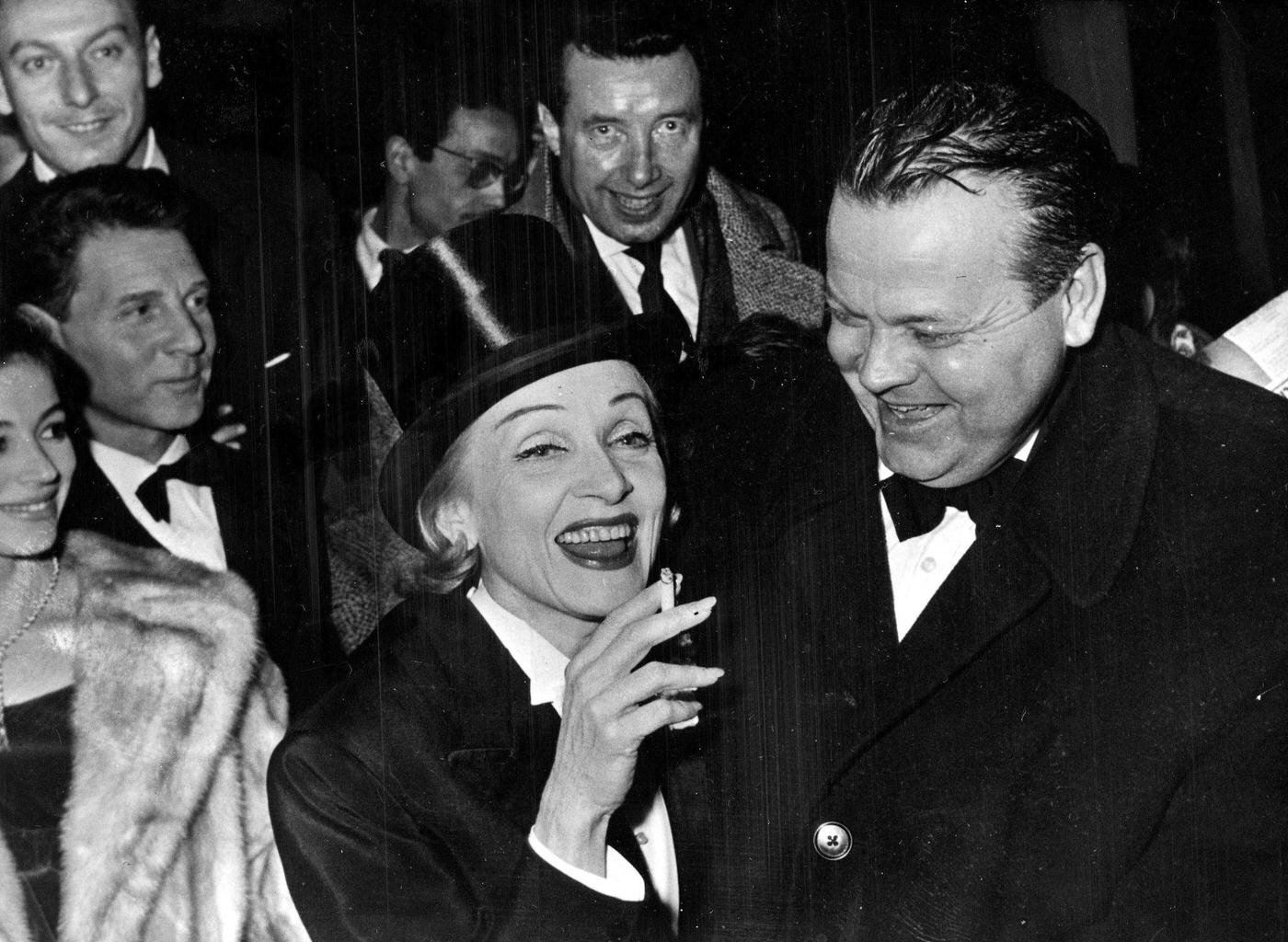 Marlene Dietrich shares a joke with US actor and director Orson Welles in 1958.