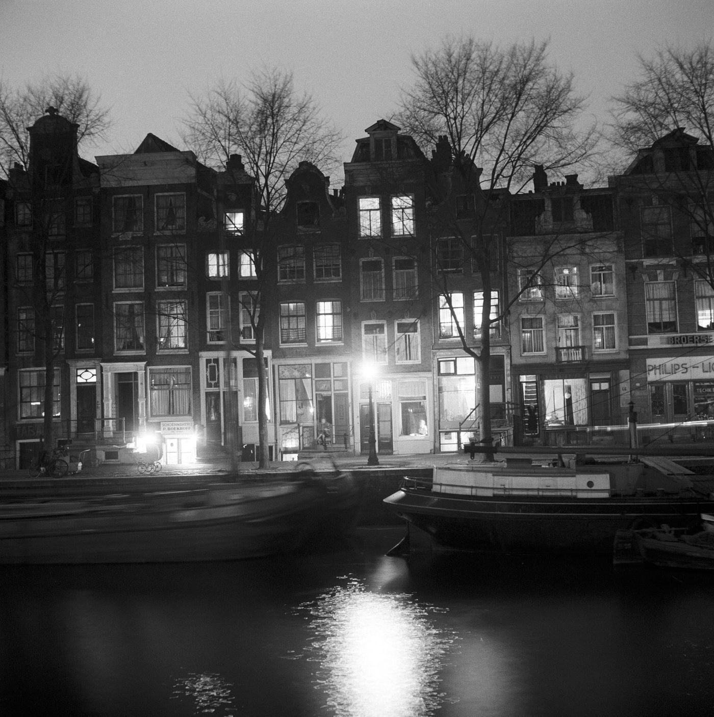 Lights switching on in typical canal houses in Amsterdam, the Netherlands, 1954.