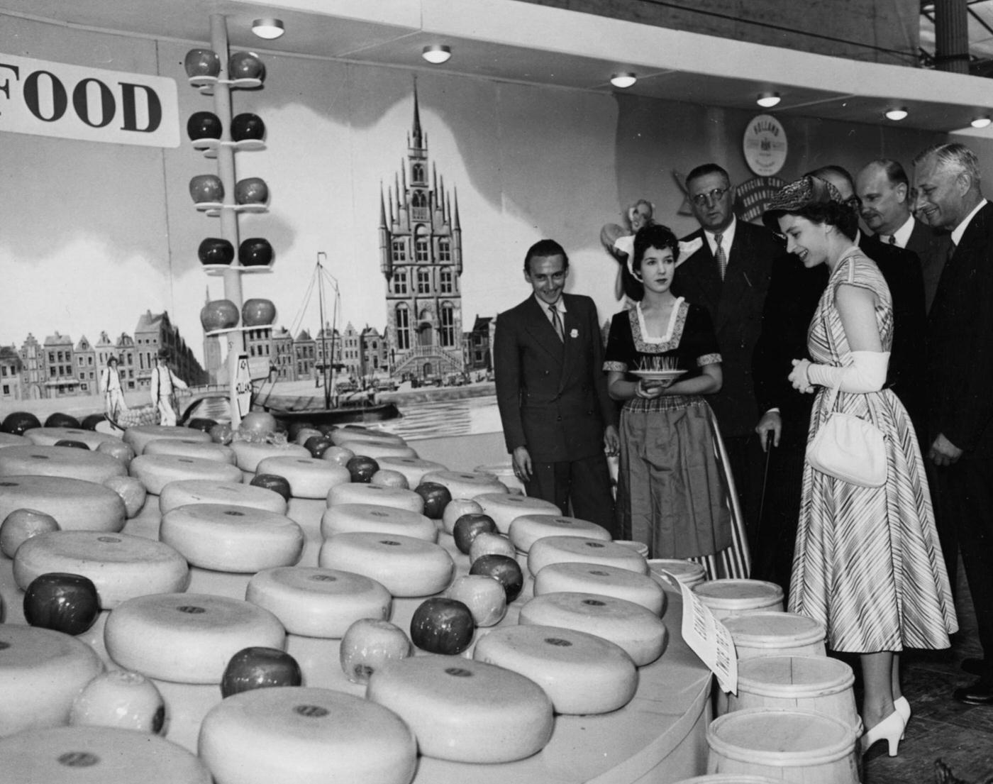 Queen Elizabeth II admires a display of Dutch cheese wheels on the Netherlands exhibit at the British Food Fair at Olympia in London, 1952.