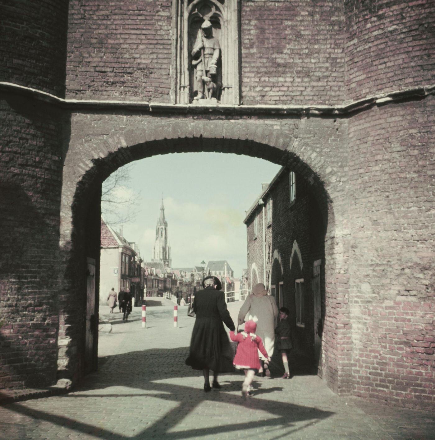 Pedestrians walk through an archway in the center of the city of Delft in the province of South Holland in the Netherlands, 1950.